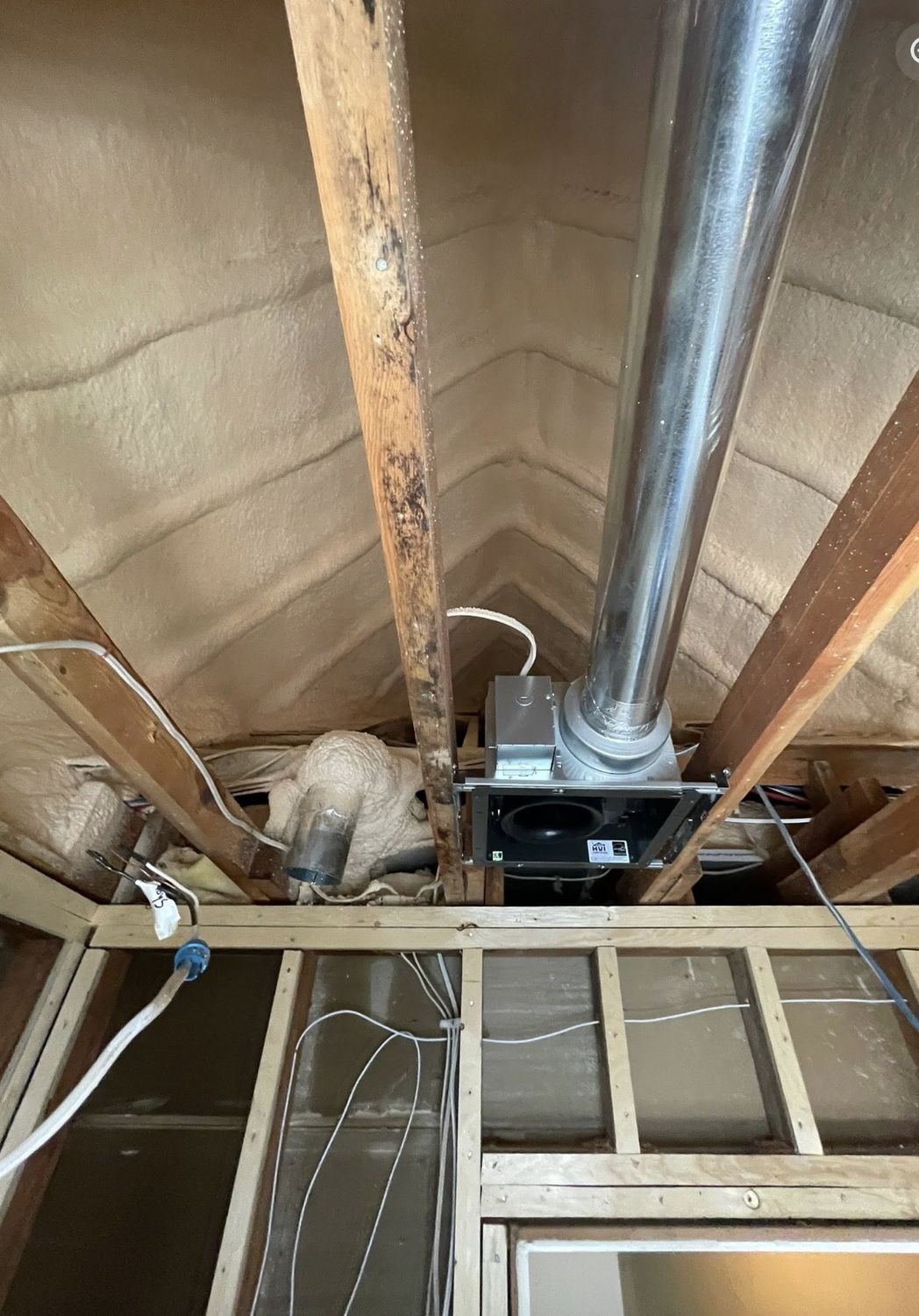 Attic spray foam installation around an exhaust fan penetration