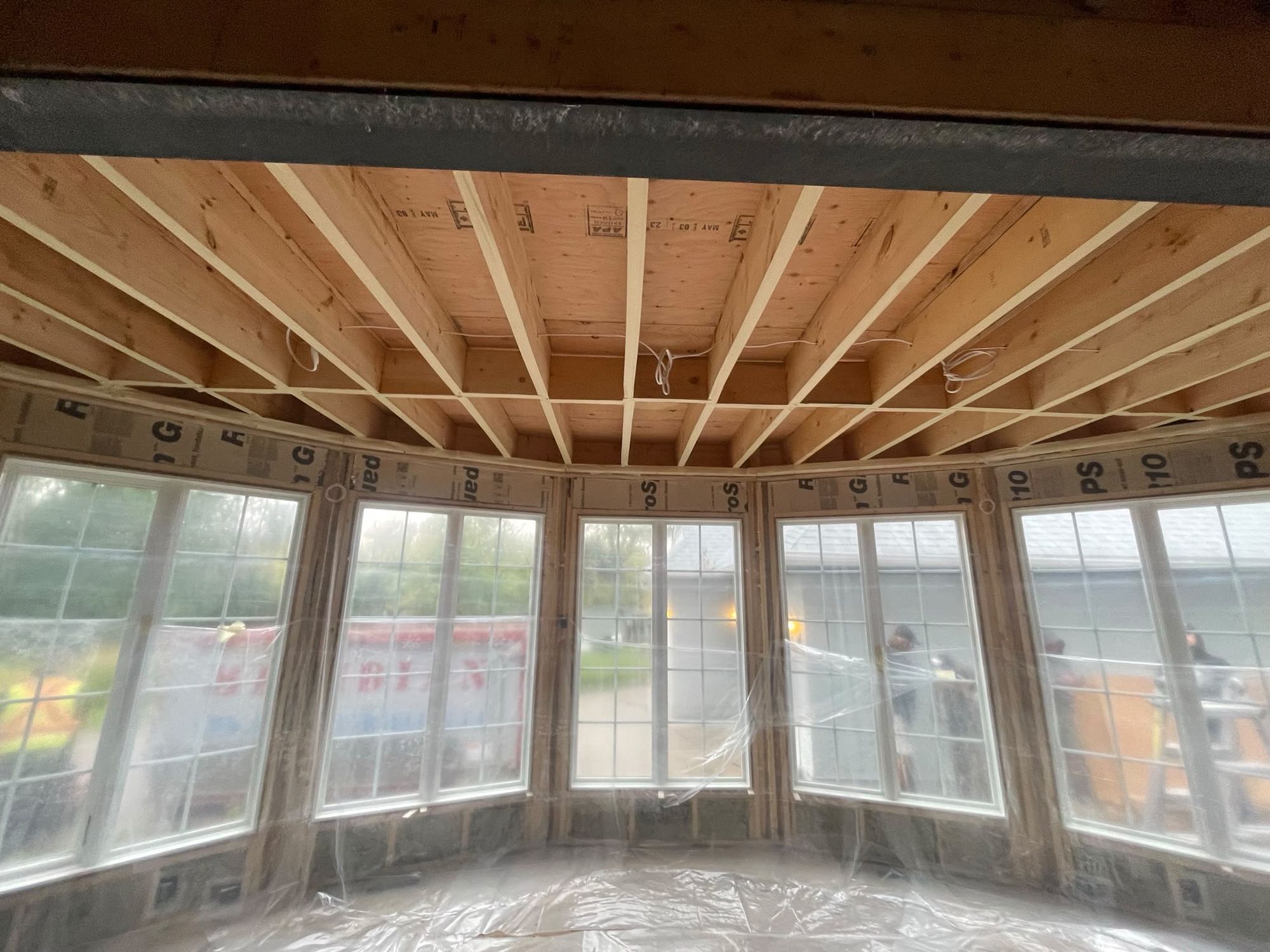 Sunroom addition ceiling with steel beam and spray foam insulation applied between rafters